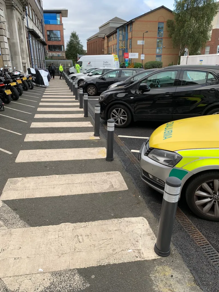 City pole cones installed along a pedestrian crossing and parking bays to protect footway space.