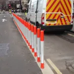 Orange and white on-highway pole cones providing lane separation on a city street
