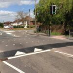 Combination raised table installed on a road, featuring Traficop rubber ramp modules with white directional arrow markings and an infilled central section for traffic calming