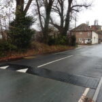 Combination raised table installed on a road, featuring Traficop rubber ramp modules with white directional arrow markings and an infilled central section for traffic calming