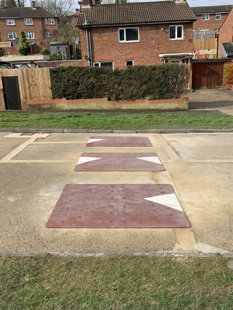 Three Traficop rubber speed cushions installed on a road, featuring red surface panels with directional arrows