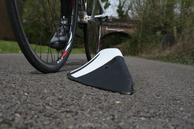 Close-up of an Orca zig-zag lane separator next to a cyclist’s wheel, illustrating the angled profile design.