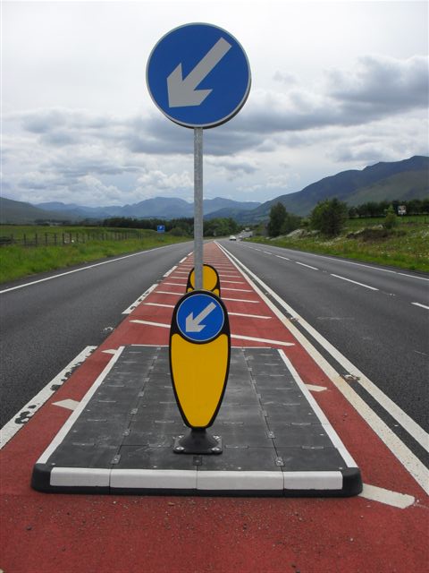 RediPave modular traffic island installed in the centre of a rural road, featuring a keep-left bollard and directional sign to guide vehicles and separate traffic lanes.
