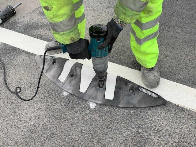 Orca MKII rubber lane divider being installed on the road surface using mechanical fixings.