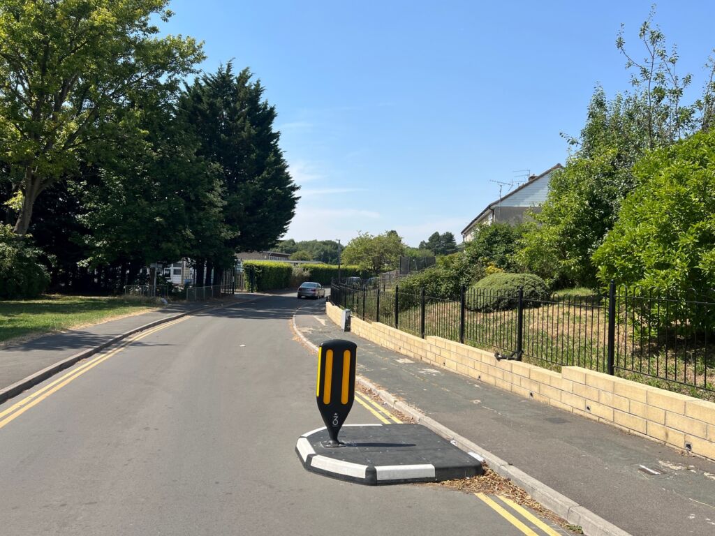 RediPave traffic island installed on a residential road, featuring a modular island base with integrated black and white markings and a central reflective bollard guiding traffic through a narrow carriageway