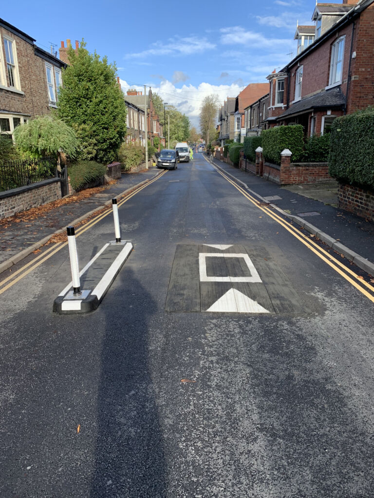 500 mm RediPave splitter island with bollards installed alongside a Traficop speed cushion on a residential street to control traffic and reduce vehicle speeds