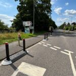Satellite islands installed along a residential road, using modular bases with bollards to narrow the carriageway and control vehicle movements near a junction.