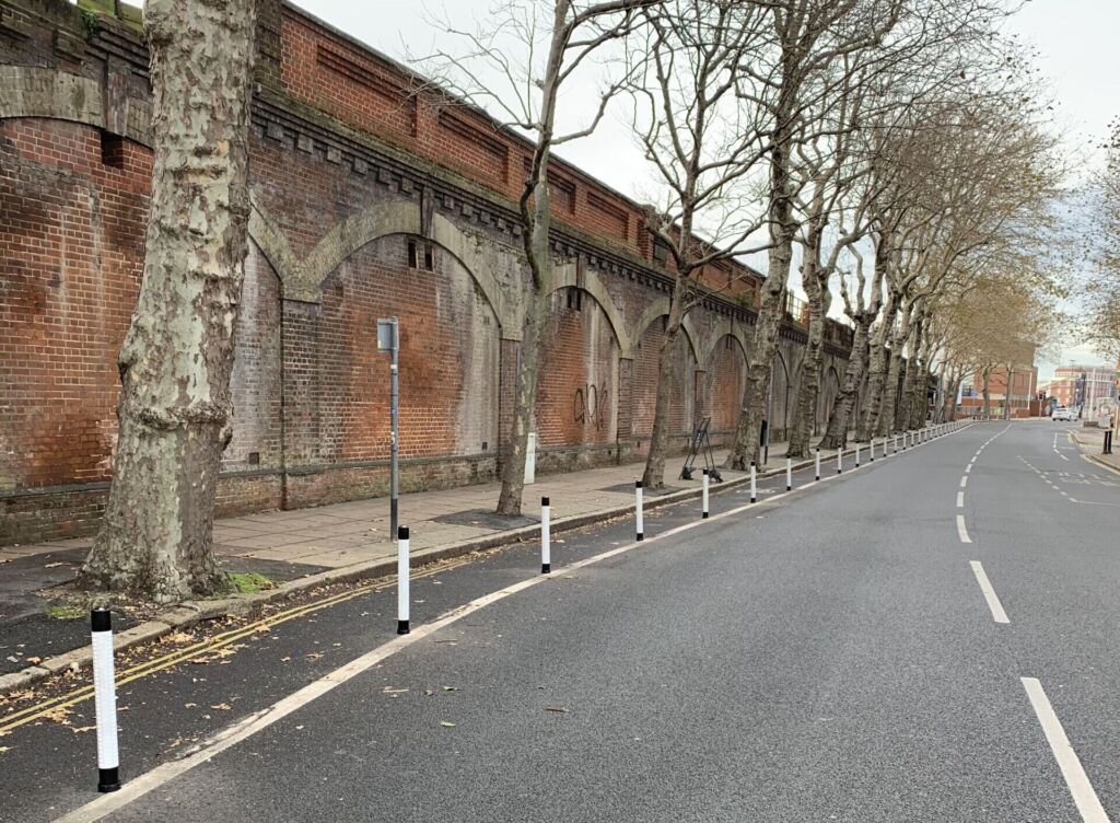 Black and white on-highway pole cones creating separation between a cycle lane and vehicle traffic