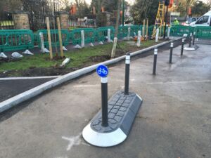 Satellite island with a modular traffic island base and bollards, including a cycle route sign, installed to separate traffic and protect cyclists and pedestrians.