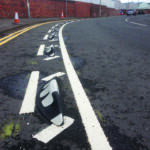 Orca tip toe design lane divider installed along a curved road, showing angled rubber modules with white reflective markings.