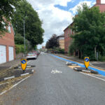Half Battered (HB) RediKerb kerbing forming traffic islands on a residential street, separating a blue cycle lane from the carriageway with keep-left bollards installed.