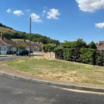 Curved modular half battered (HB) kerbing installed along a grass verge to define the carriageway edge on a residential street.