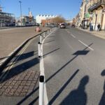 Black and white on-highway pole cones creating separation between a cycle lane and vehicle traffic