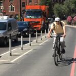 Black and white on-highway pole cones creating separation between a cycle lane and vehicle traffic