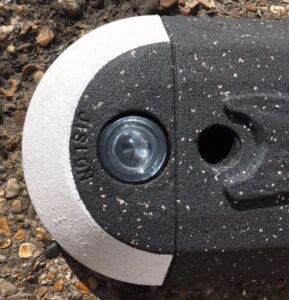 Close-up of a Milestone island end unit showing an integrated glass light dome set into the kerb module, with contrasting black and white finish for visibility.