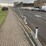 Milestone kerb unit with reflective bollards separating a cycle lane from traffic.