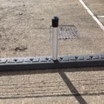 Milestone traffic island with flexible bollard installed on concrete surface.