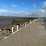 Milestone islands with pole cones installed along a coastal path, forming a continuous protected edge to separate and safeguard pedestrians and cyclists from the adjacent roadway.