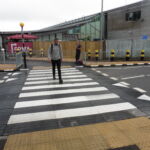 Raised rubber table with integrated zebra crossing installed at an airport access road, providing a level pedestrian crossing and traffic calming
