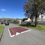 Raised rubber speed table installed on a residential road, with contrasting surface and road markings to slow vehicle traffic near a pedestrian area.