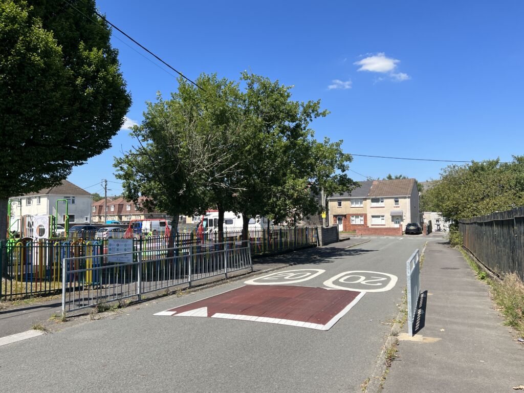 Raised rubber speed table installed on a residential road, with contrasting surface and road markings to slow vehicle traffic near a pedestrian area.