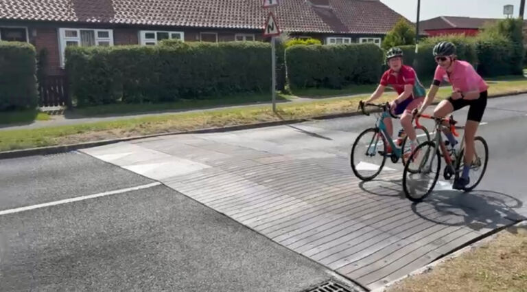Sinusoidal rubber ramp installed on a residential road, allowing vehicles and cyclists to pass smoothly while reducing traffic speed.