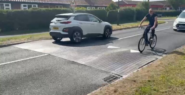 Sinusoidal rubber ramp installed on a residential road, allowing vehicles and cyclists to pass smoothly while reducing traffic speed.