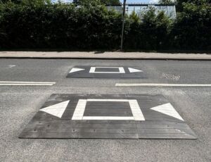 Traficop rubber speed cushions installed on a roadway, featuring white markings and directional arrows for traffic calming.