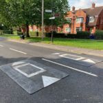 Traficop rubber speed cushions installed on a residential road, featuring white perimeter markings and large directional arrows for traffic guidance.