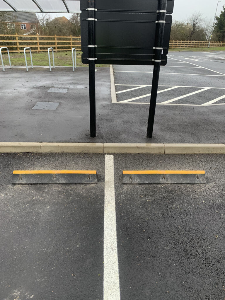 TruckStop 115 heavy-duty wheel stop with high-visibility yellow markings installed on a paved surface.
