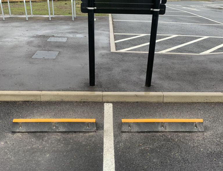 TruckStop 115 heavy-duty wheel stop with high-visibility markings installed to control vehicle stopping position.