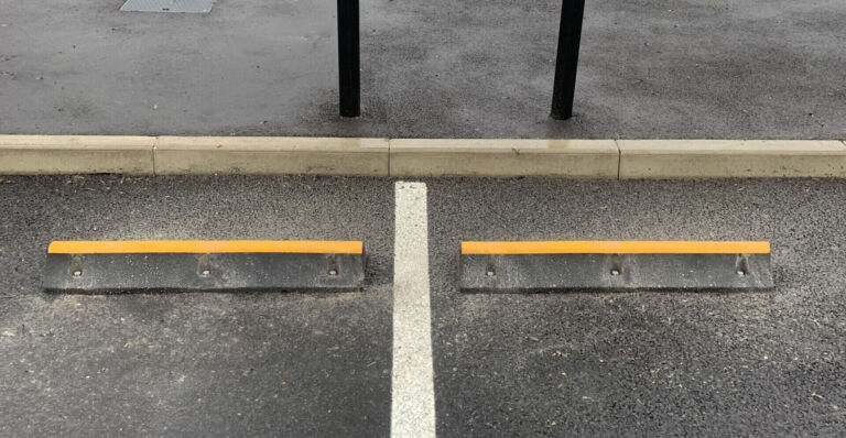 TruckStop 115 heavy-duty wheel stop with high-visibility markings installed to control vehicle stopping position.