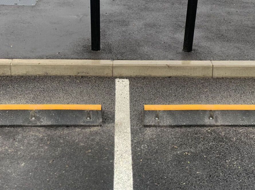 TruckStop 115 heavy-duty wheel stop with high-visibility markings installed to control vehicle stopping position.