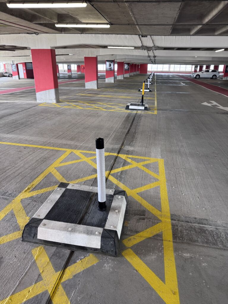 Black and white kerbing system in indoor car park, used to separate marked areas and control traffic flow.