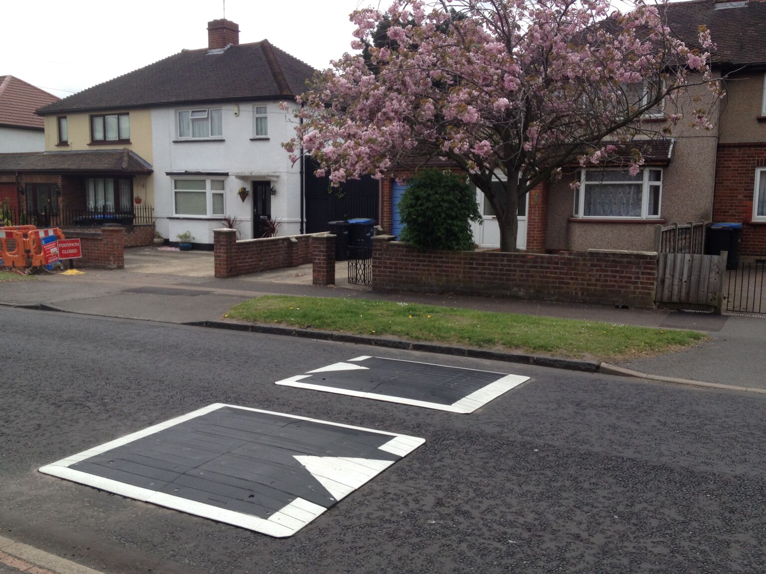 Black and white rubber speed cushions installed on residential road for traffic calming.