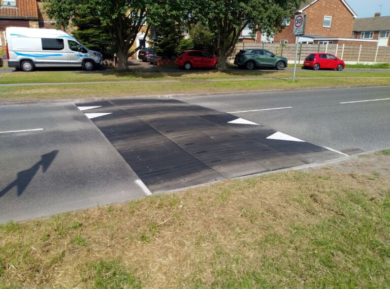 Sinusoidal rubber ramp installed on a residential road, allowing vehicles and cyclists to pass smoothly while reducing traffic speed.
