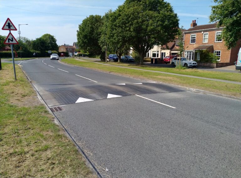 Sinusoidal rubber ramp installed on a residential road, allowing vehicles and cyclists to pass smoothly while reducing traffic speed.