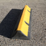 TruckStop 115 heavy-duty wheel stop with extended high-visibility markings installed to control vehicle stopping position.